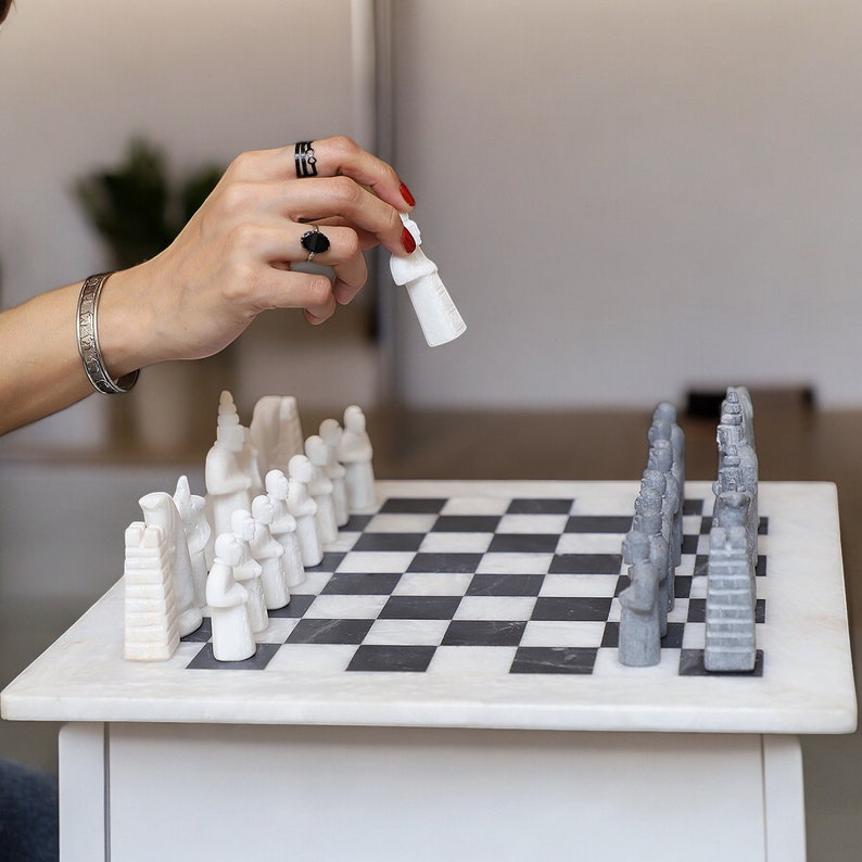 White and Black Matt Marble Statue Chess Set placing on the table and a women playing chess